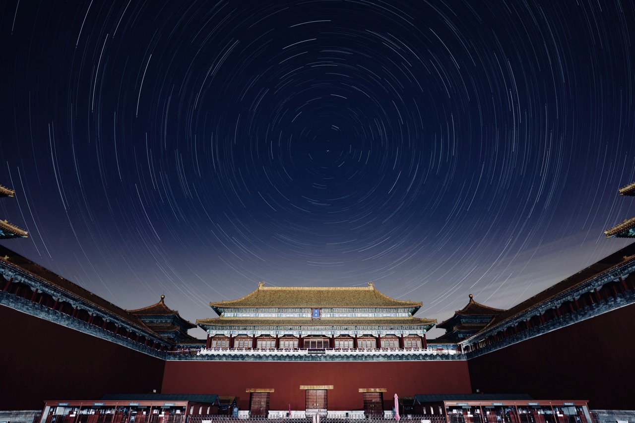 Star trails above the midnight silhouette of Wumen Gate in the Forbidden City.