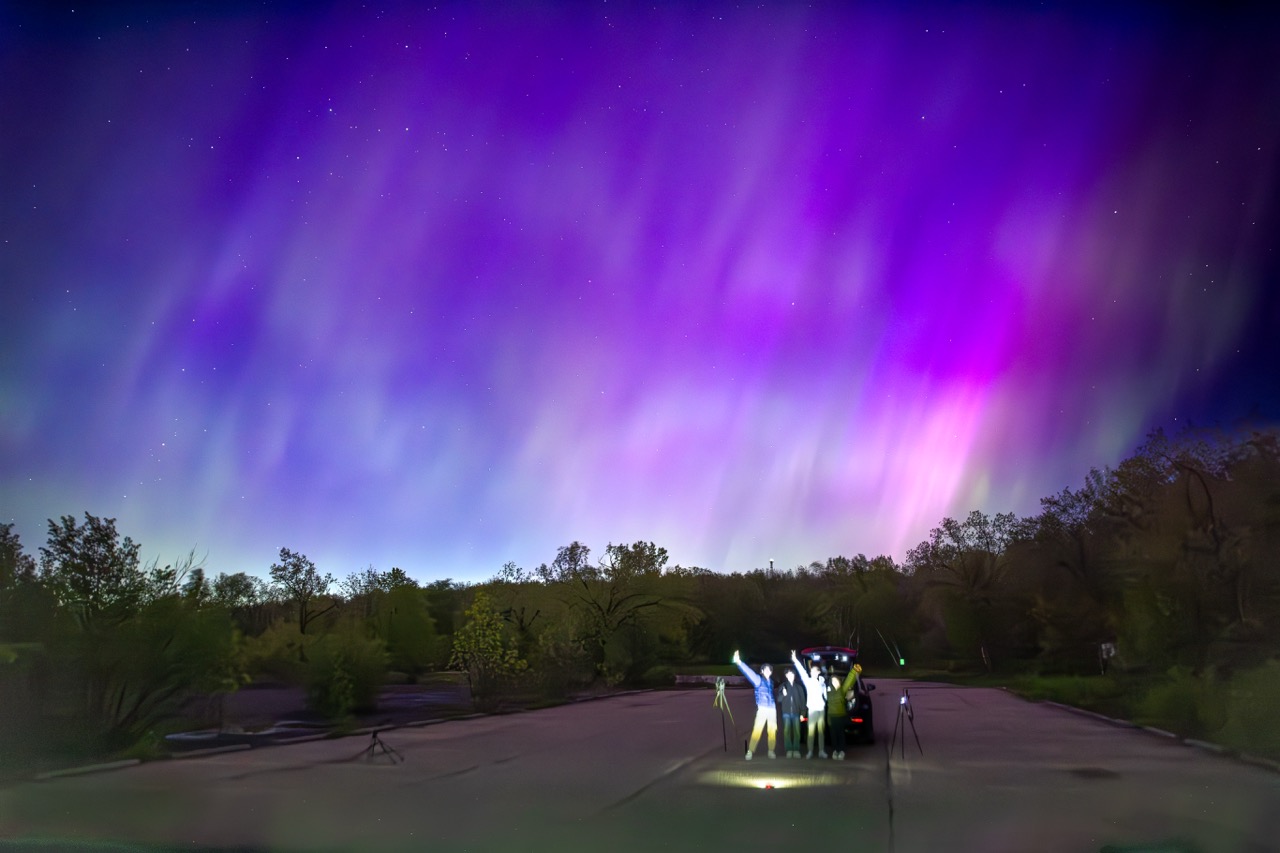 Silhouettes gathered beneath magenta aurora curtains.