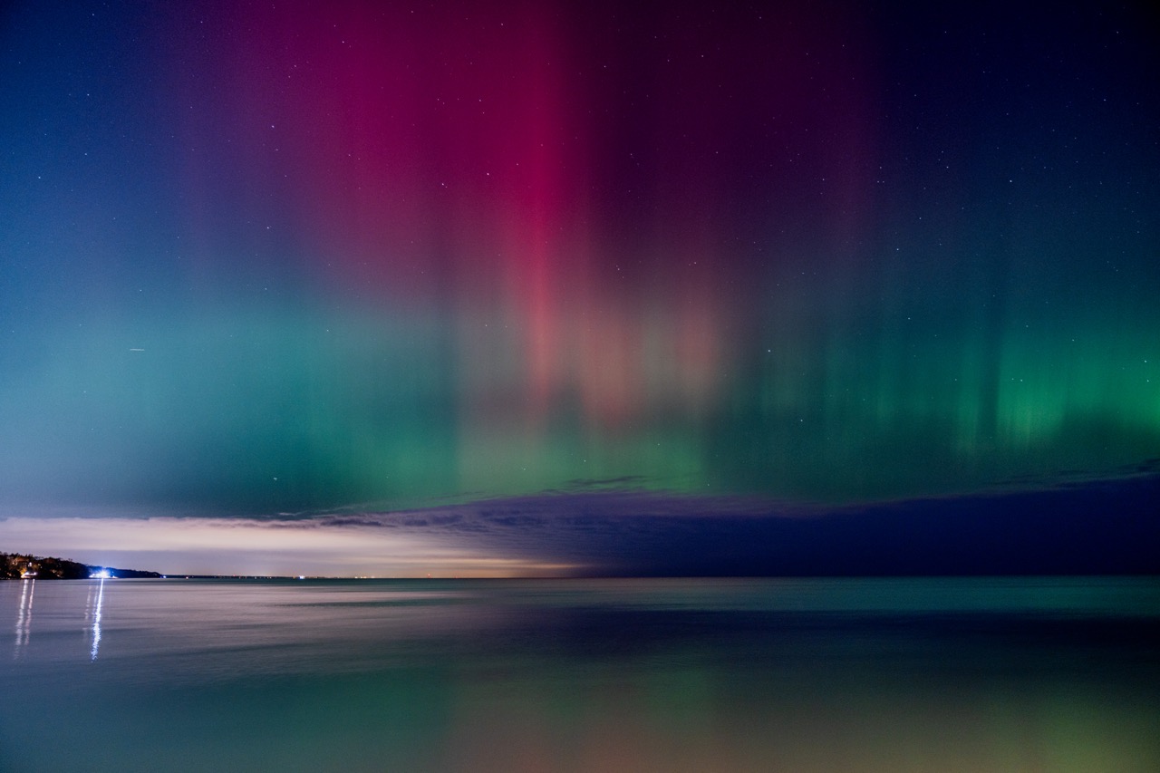 Red and green aurora curtains above Lake Michigan.