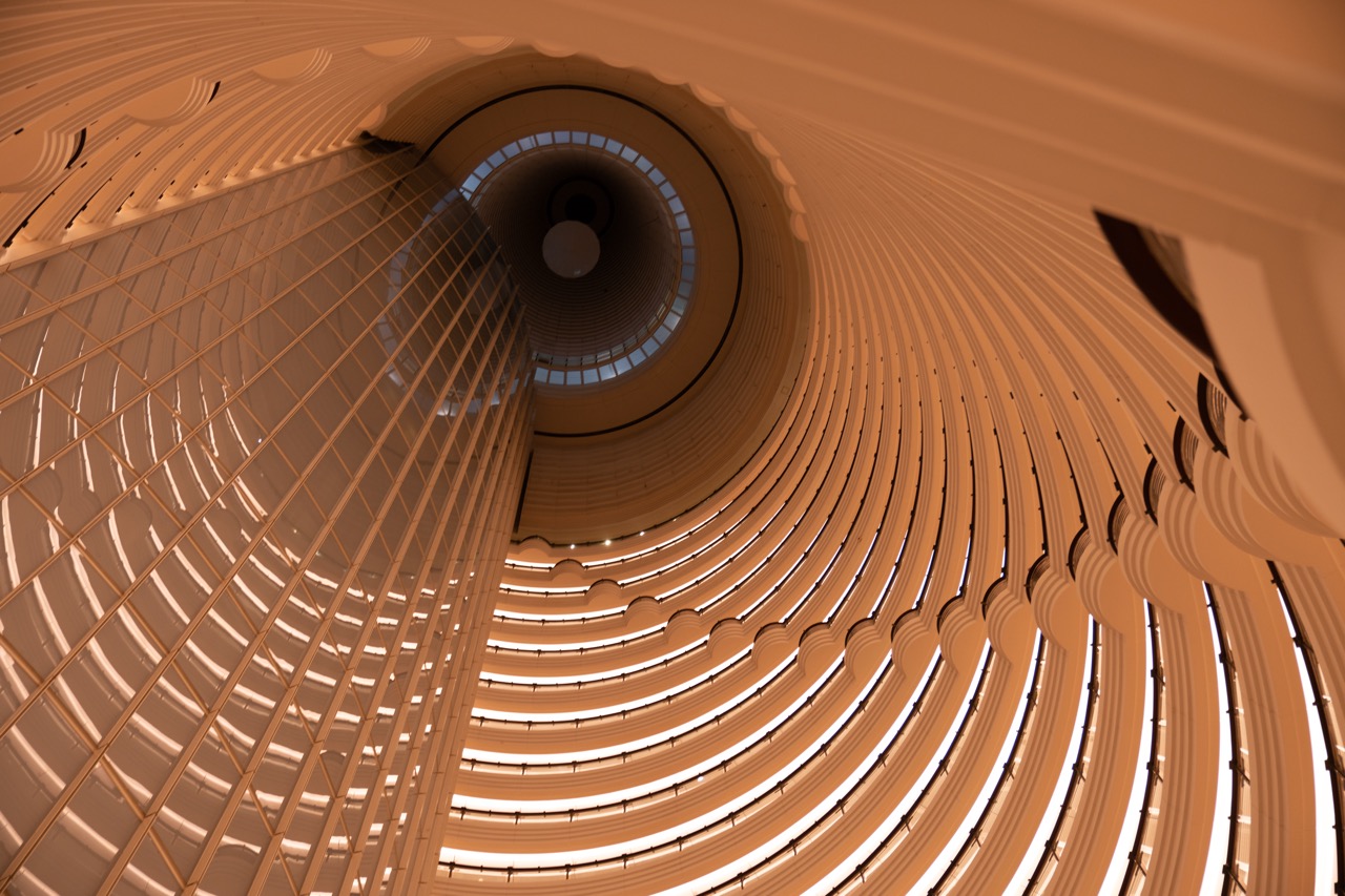 Glass atrium at Jinmao Tower with layered light reflections.