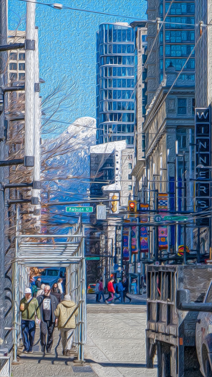 Daylight view down Vancouver's Robson Street with snow mountains beyond.