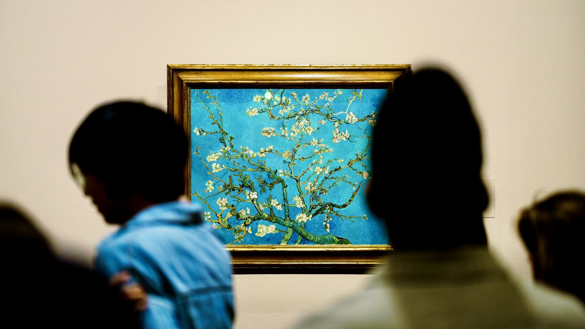 Visitors silhouetted before Van Gogh's Almond Blossoms painting.